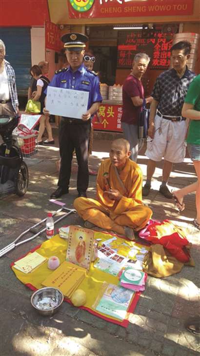 假僧人街头乞讨 城管站他身后举牌警示别上当_城管-僧人-佛教-队员-市民