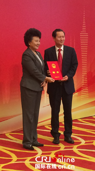 国务院侨办主任裘援平（左）向英国中文教育促进会会长伍善雄颁发聘书