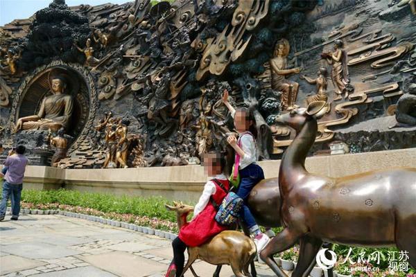 也有不少游客让孩子爬上浮雕下的小雕塑，拍照留念。景区呼吁，请游客文明出行。