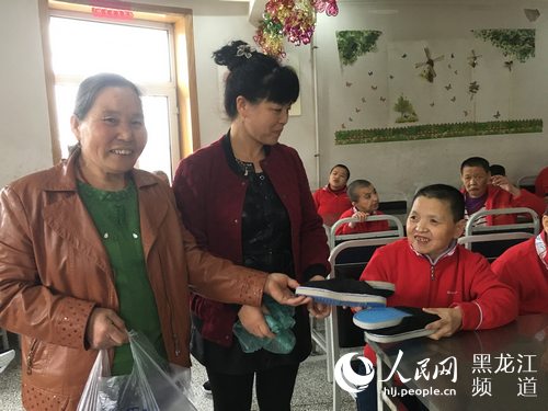 作者妈妈（左一）和表姐将爱心布鞋送到福利院院民手中。