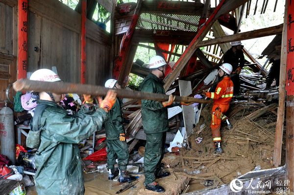 当地干部与武警官兵在清理受损房屋，营救被困群众。邓忠卫摄