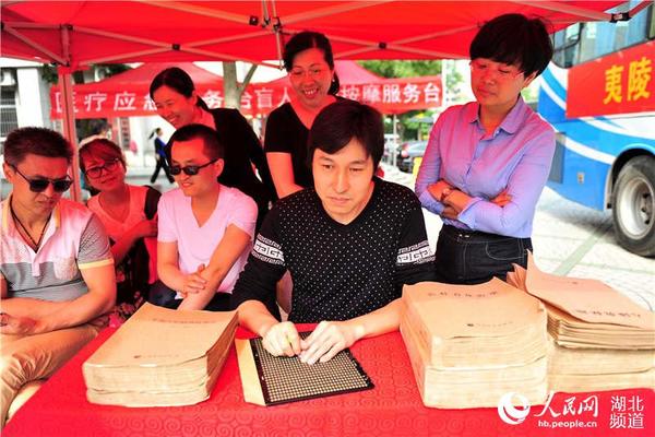 一位盲人在盲文展示咨询台演示书写盲文。