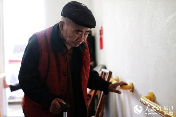 76岁的老人周啟祥在家里靠扶手行走。（朱虹 摄）