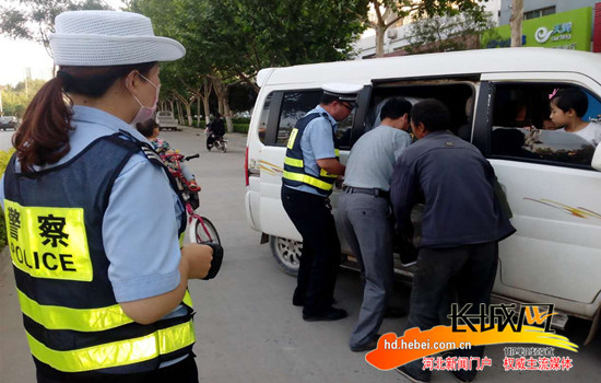 交警和众人一起将醉汉抬上车。 张波 摄