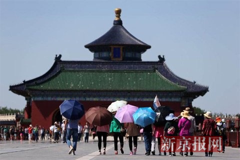 一群游客戴帽子、打伞遮阳。新京报记者 薛珺 摄