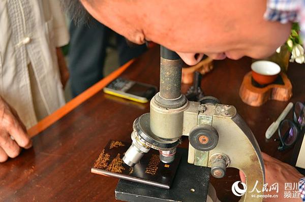 记者通过显微镜欣赏贾氏微刻作品。（刘浏 摄）