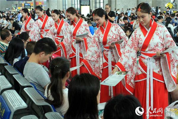 身着汉服的工作人员在候车室向旅客发放中国古代文明诗词和文明旅游出行的宣传页。刘卫兵 摄