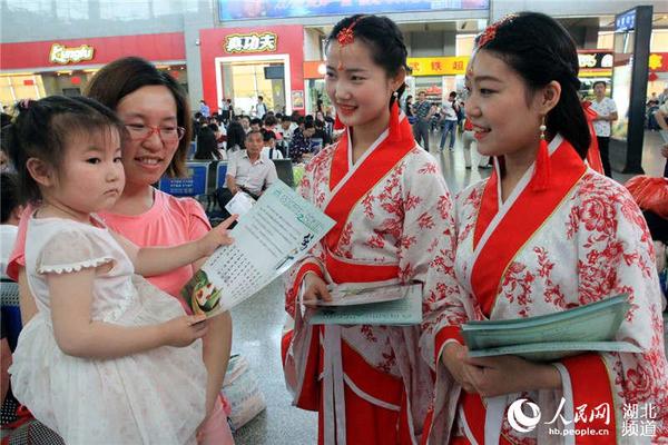 身着汉服的工作人员在候车室向旅客发放中国古代文明诗词和文明旅游出行的宣传页。刘卫兵 摄