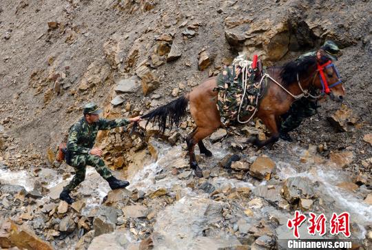 图为边防官兵玉素甫江库尔班拽着马匹尾巴前行. 吴明贤 摄