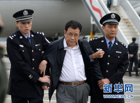 2015年05月9日，在北京首都国际机场，李华波（中）被押解下飞机。新华社记者 陈晔华 摄