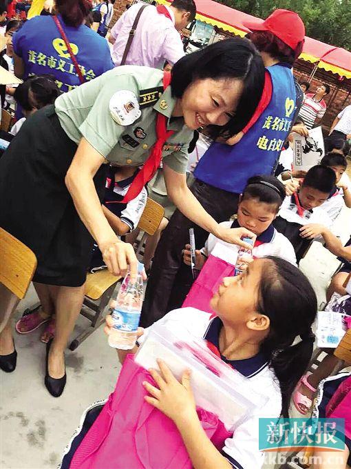 广东省女书法家协会副主席梁江萍向学生发放笔墨纸砚及水彩颜料等书画工具。