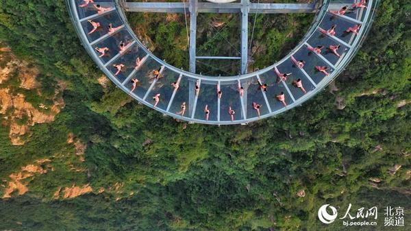 伴着清晨的旭日，瑜珈爱好者在玻璃观景台上练起了瑜珈。