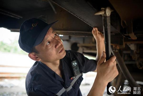 罗明铭检查车辆底部部件的状况。