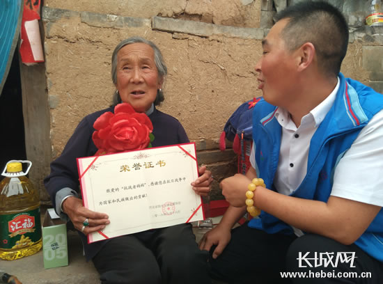 志愿者为抗日老妈妈送上纪念杯和荣誉证书。