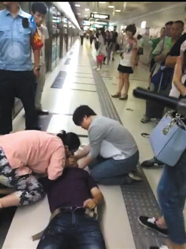 一位女士志愿对倒地的金波进行人工呼吸。(视频截图)图片来源：新京报