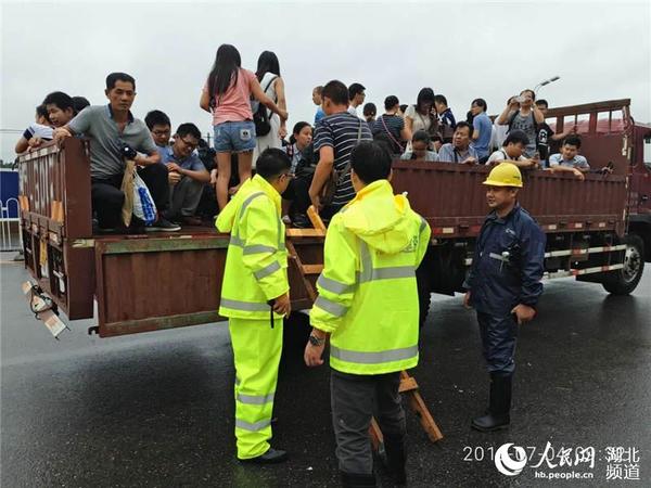 身着反光雨衣的光谷建设公司员工正在帮助群众摆渡。