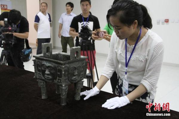 参展博物馆代表检查文物“大禾人面纹方鼎”。 中新社记者 钟欣摄