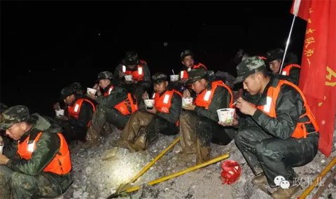 图：7月4日晚，武警安徽总队第二支队官兵在巢湖市柘皋河堤坝上补充能量。