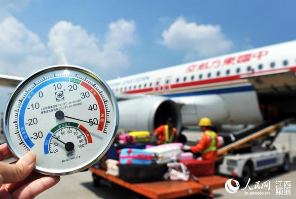 南昌昌北机场停机坪的温度超过50℃，飞机落地，地勤人员忙着装卸行李。