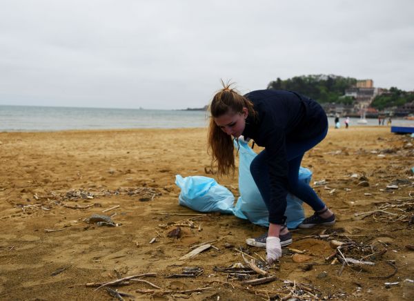 图说：一名志愿者在海滩上捡垃圾。（新华社）