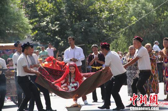 维吾尔族婚礼中有抛举新娘的习俗，营造喜庆气氛。表现出他们幽默、乐观的性格。　朱景朝　摄