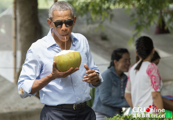 　　当地时间9月7日，老挝琅勃拉邦，美国总统奥巴马访问琅勃拉邦，在湄公河旁短暂停留，街边手抱椰子品尝椰子汁。图片来源：视觉中国