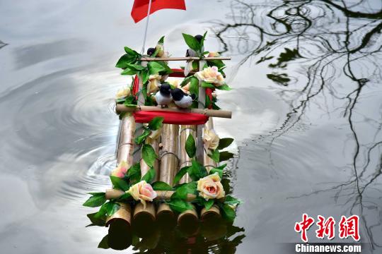 彩船用竹子制作,上面挂着彩带、绣花、塑料花,还放有喜鹊。 程景伟 摄 随着中国传统中秋佳节来临,按照壮家中秋传统习俗,广东省清远市连山壮族瑶族自治县金子山下的壮家村寨数名姑娘,9月10日来到了金子山溪流池里放漂彩船,祈盼遇到好姻缘。 壮家姑娘们当天身穿传统民族服饰,手提自制的彩船,彩船用竹子制作,上面挂着彩带、绣花、塑料花等装饰品。彩船还放有在壮家人中代表喜气、吉祥、婚姻美满幸福的喜鹊。 在现场,姑娘们将彩船放到水里,并用力推向远方,希望彩船越漂越远。 据壮族姑娘介绍,在当地壮家传统里,中秋放彩船祈求