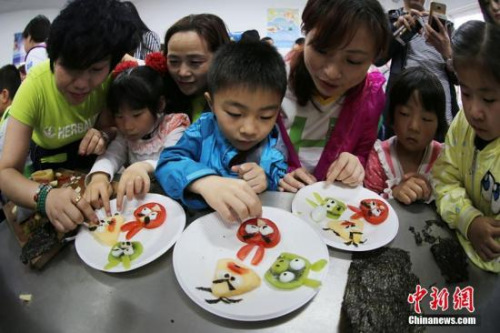 资料图。志愿者与南京留守儿童共同制作富有创意的水果拼盘。泱波摄
