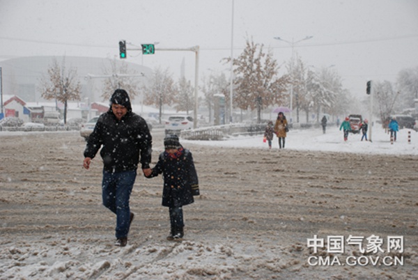 11日，新疆塔城遭遇强降雪，行人行走在湿滑路面上。图片来源：中国气象网