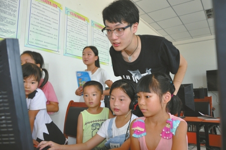 志愿者教孩子们玩儿电脑。