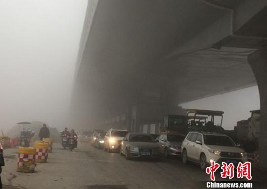 图为郑州市区，部分车辆已经打开车灯缓慢行驶在马路上。　王秋兰 摄