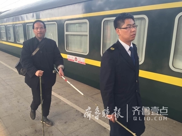 列车员倪俊阳引领着盲人乘客行走。