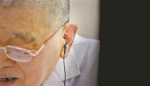 图③段亚亭戴上眼镜、助听器给病人看病。