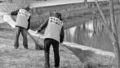 长春公园内的工作人员身着“标语马甲”正在打扫卫生 新文化记者 蒋盛松 摄
