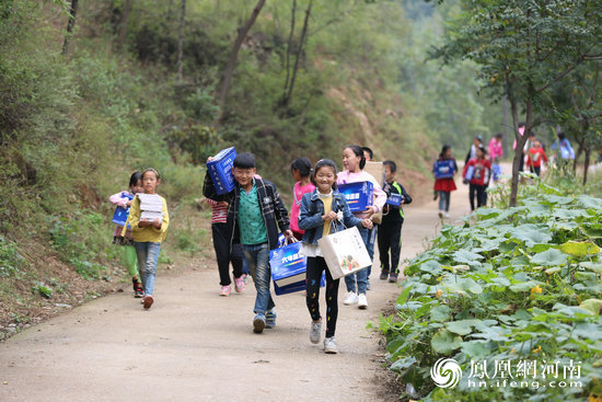 由于学校门前的小路狭窄,爱心物资车只能就近停下由人工搬运,师生们也自发来帮忙。
