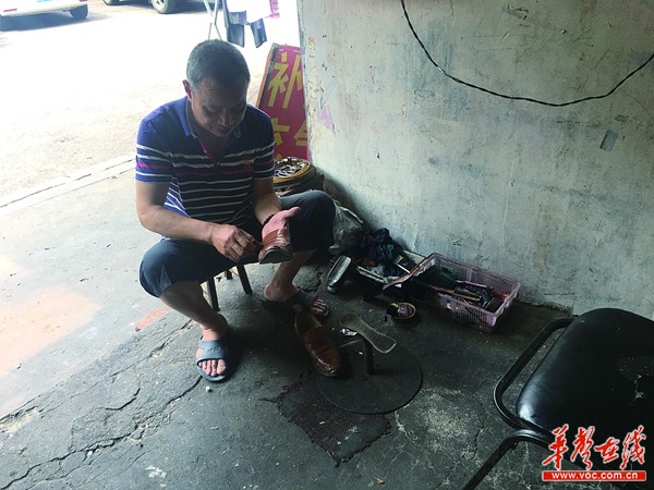 5月17日上午，周应龙在为客户擦拭皮鞋。 记者张洋银摄
