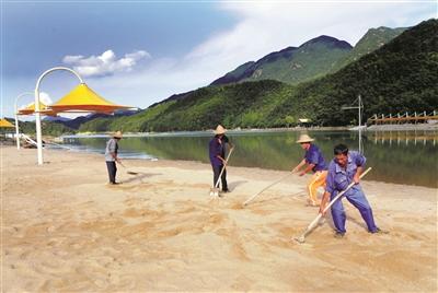 图为施工人员正在平整人工沙滩.